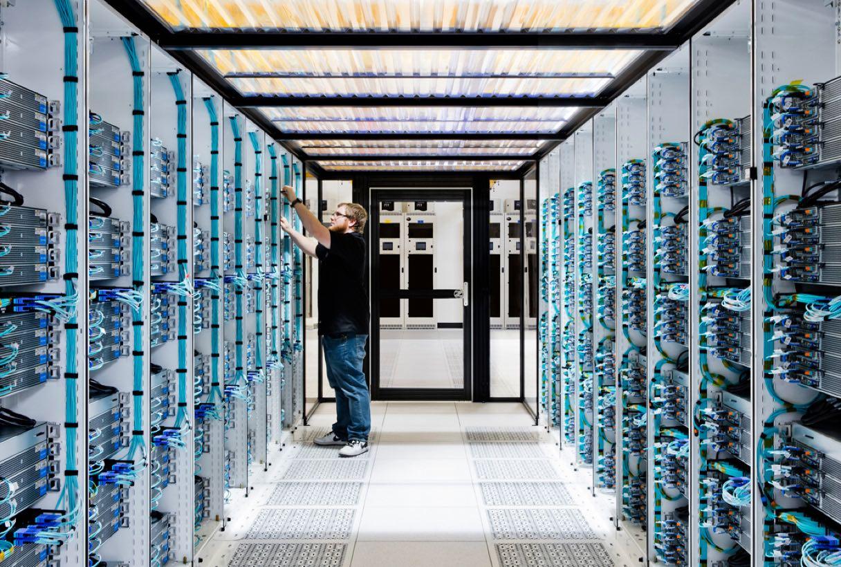 Man configuring networking equipment in a hallway of network applicance.